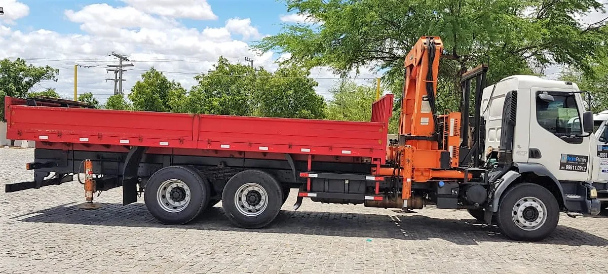 Caminhão munck com lança recolhida, parado em via de obra